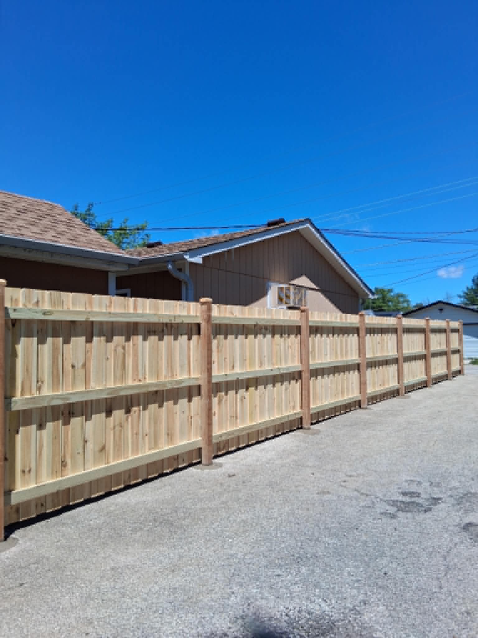 Long wooden privacy fence installed beside a residential driveway