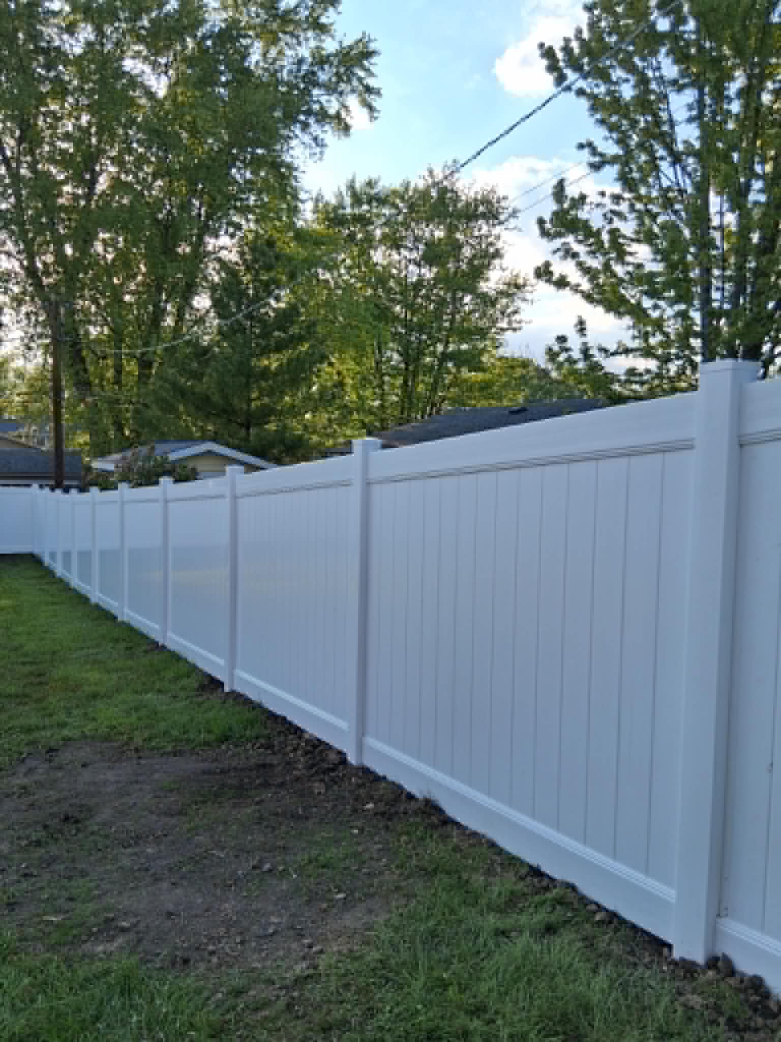 White vinyl privacy fence installed along a backyard