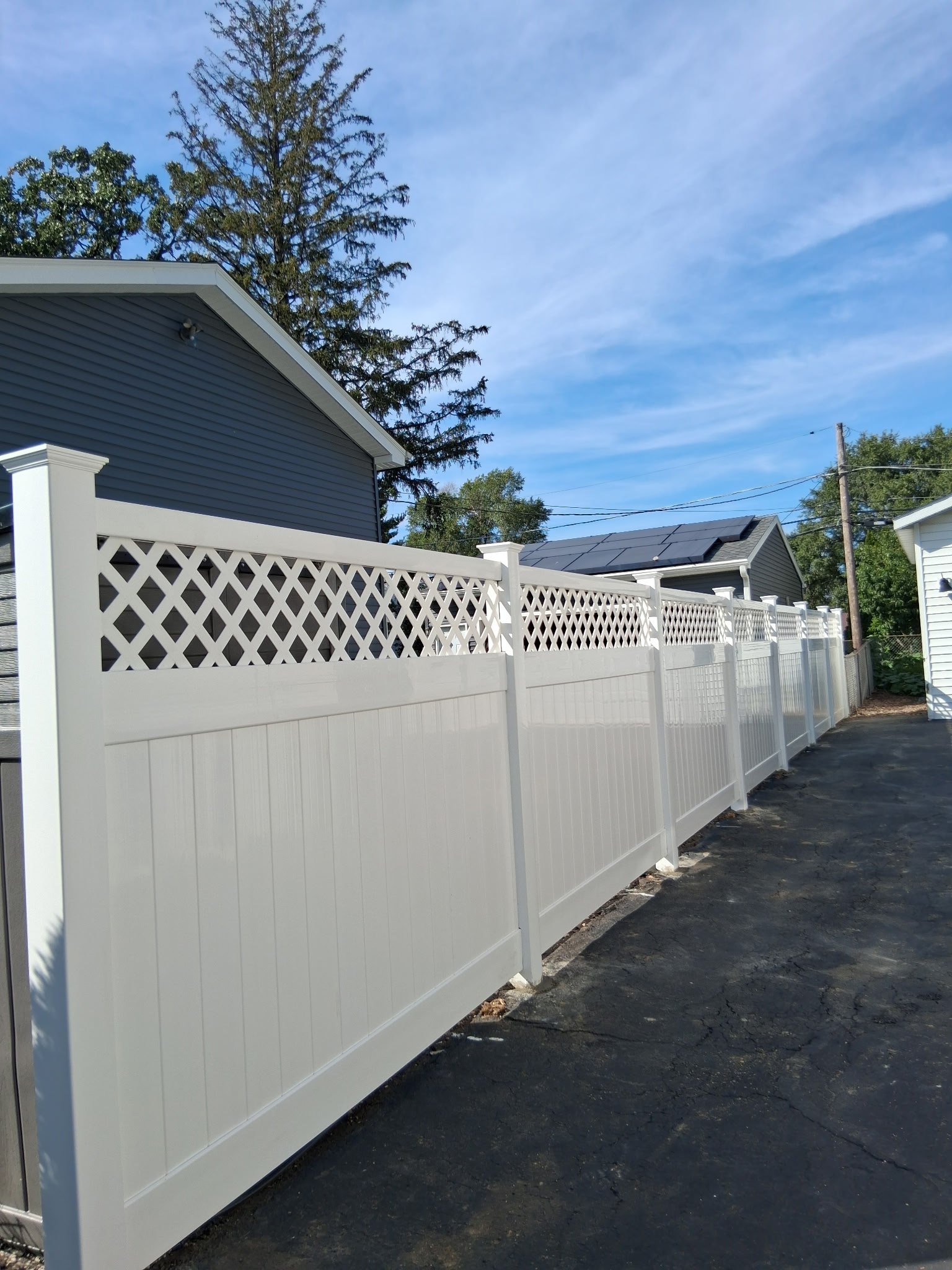 White vinyl privacy fence with lattice top along a driveway